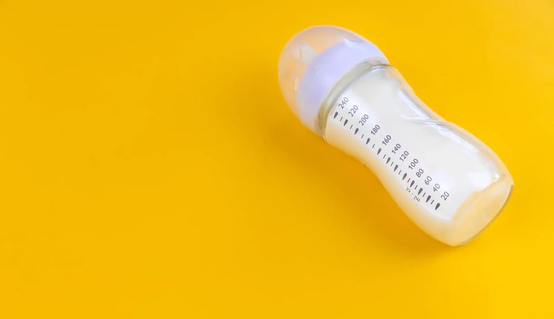 A baby bottle on a bright yellow background