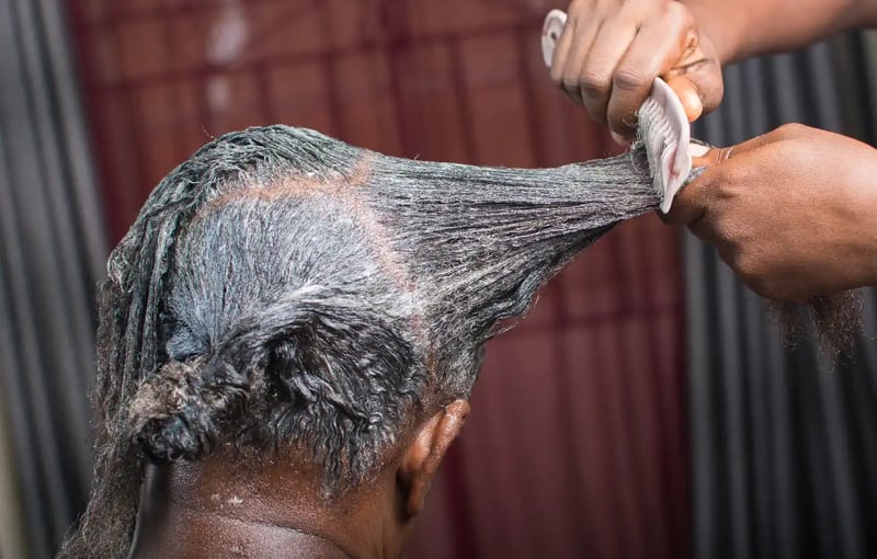 Hair relaxer being combed into a woman's hair