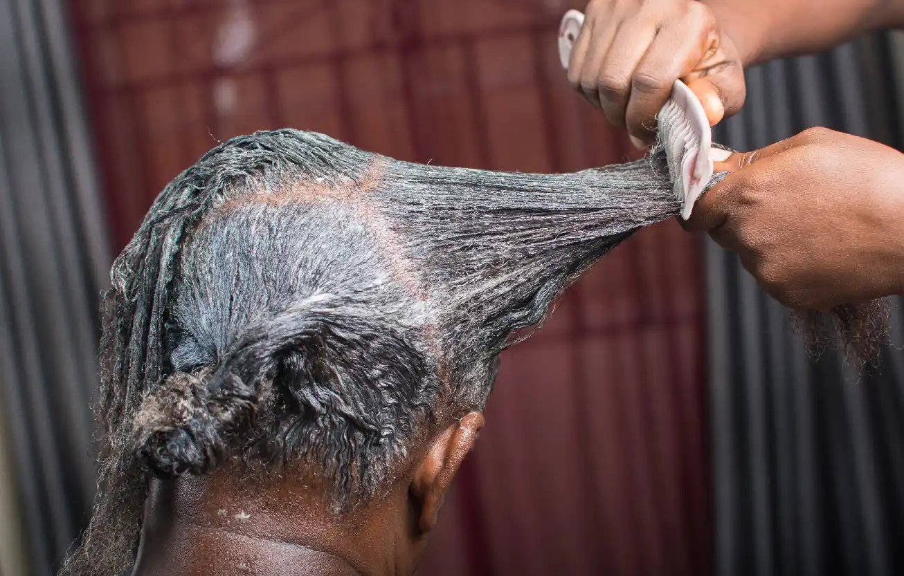 Hair relaxer being combed into a woman's hair