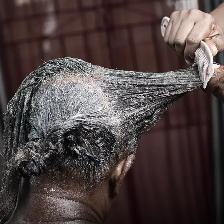 Hair relaxer being combed into a woman's hair